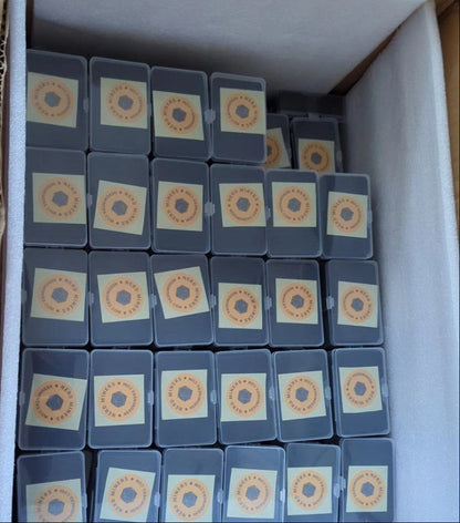 Box filled with small containers holding cards with circular designs on a cardboard surface.