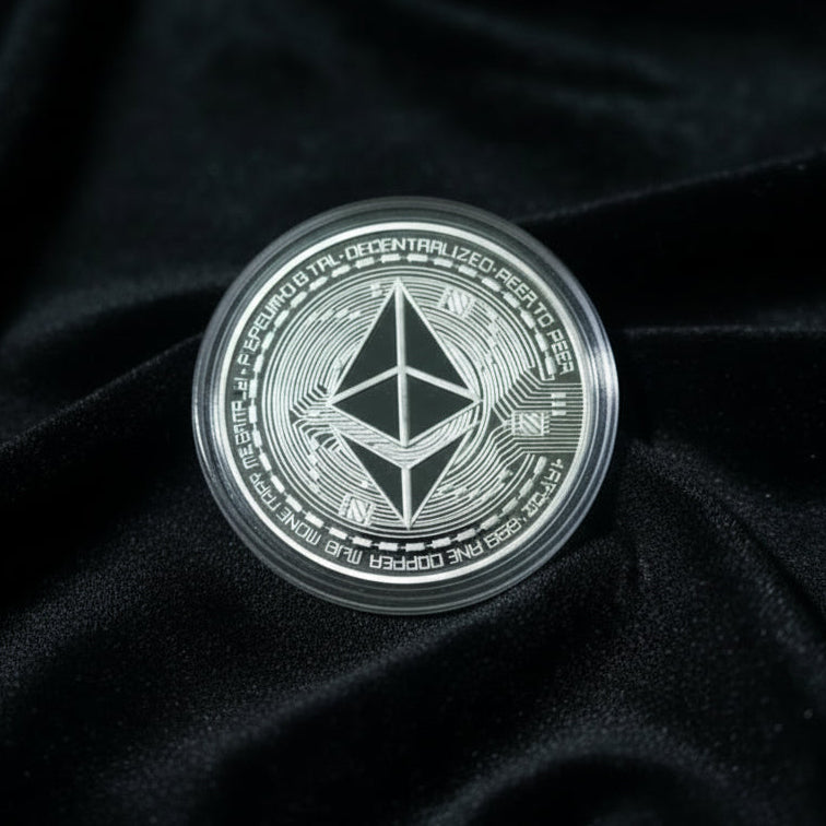 Hand holding a silver Ethereum coin against a velvet surface