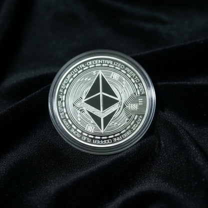 Hand holding a silver Ethereum coin against a velvet surface