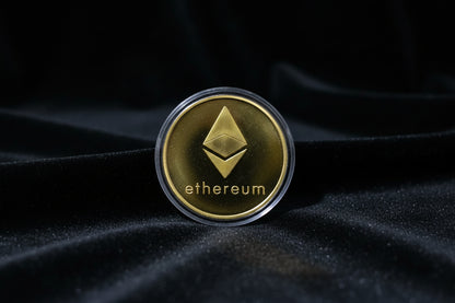 Gold Ethereum coin in a clear holder against a textured background