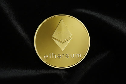 Gold Ethereum coin on black fabric