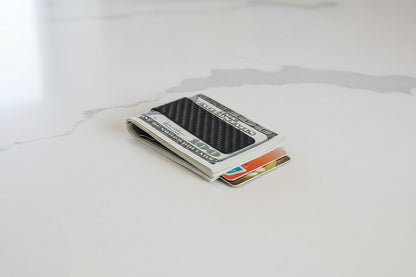 Money clip holding a stack of dollar bills and cards on a white background