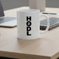 White mug with 'HODL' text on a desk with a laptop and keyboard.