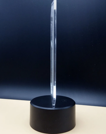 Clear crystal object on a black base against a dark blue background