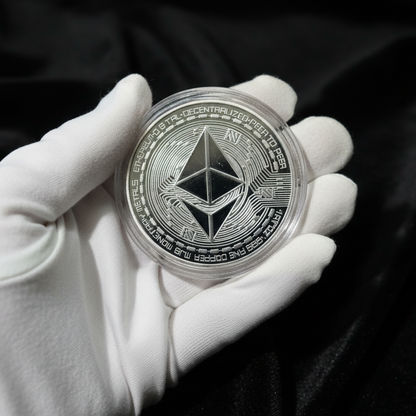 Hand holding a silver coin with a geometric design on a wooden surface