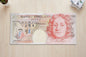 Fifty-pound Bank of England note on a wooden surface