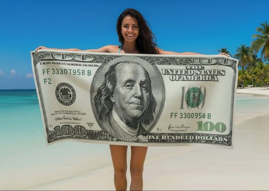 Woman holding a large dollar bill on a beach