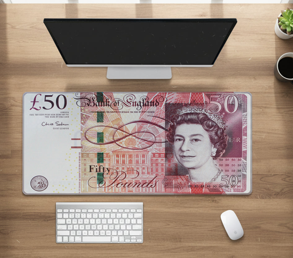 Desk setup with a British £50 banknote mouse pad on a wooden surface.
