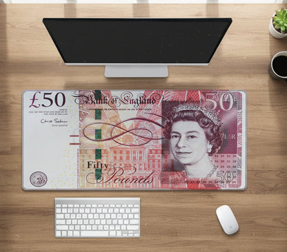 Desk setup with a British £50 banknote mouse pad on a wooden surface.
